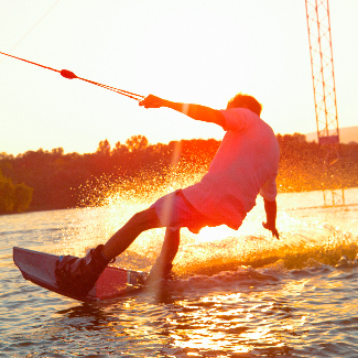 Person wakeboards at sunset.