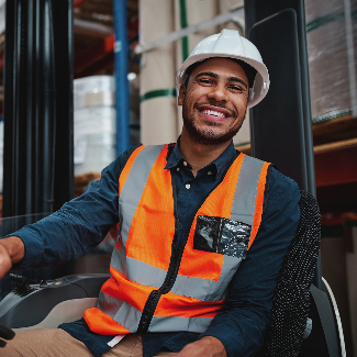 A forklift operator smiles in an orange safety vest and white hard hat.