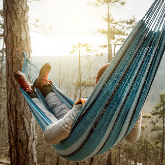 Person in boots enjoys view of a mountain from a hammock on a chilly day.
